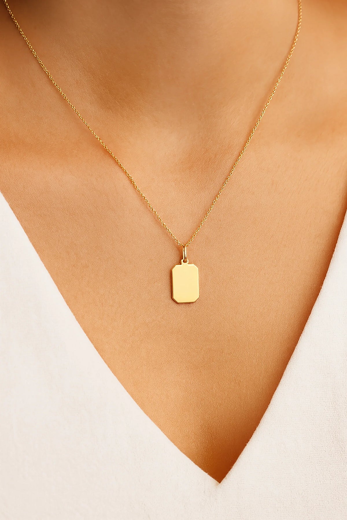 LuccheGold 14K gold personalized rectangle tag pendant on a gold chain worn by a woman